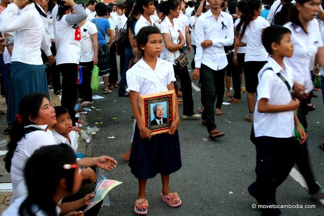 A young Cambodian girl holds a framed photograph of Norodom Sihanouk. 
