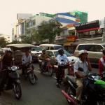 Phnom Penh traffic, including tuk tuks, SUVs and moto drivers busy driving and texting.